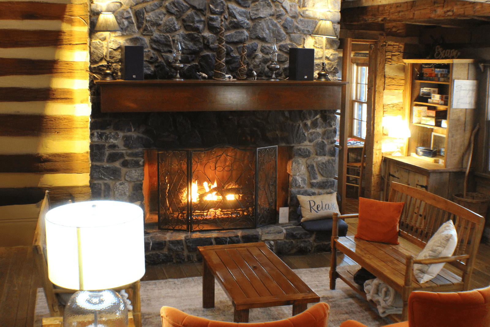 Cozy living room featuring a stone fireplace, wooden furniture, and warm lighting.
