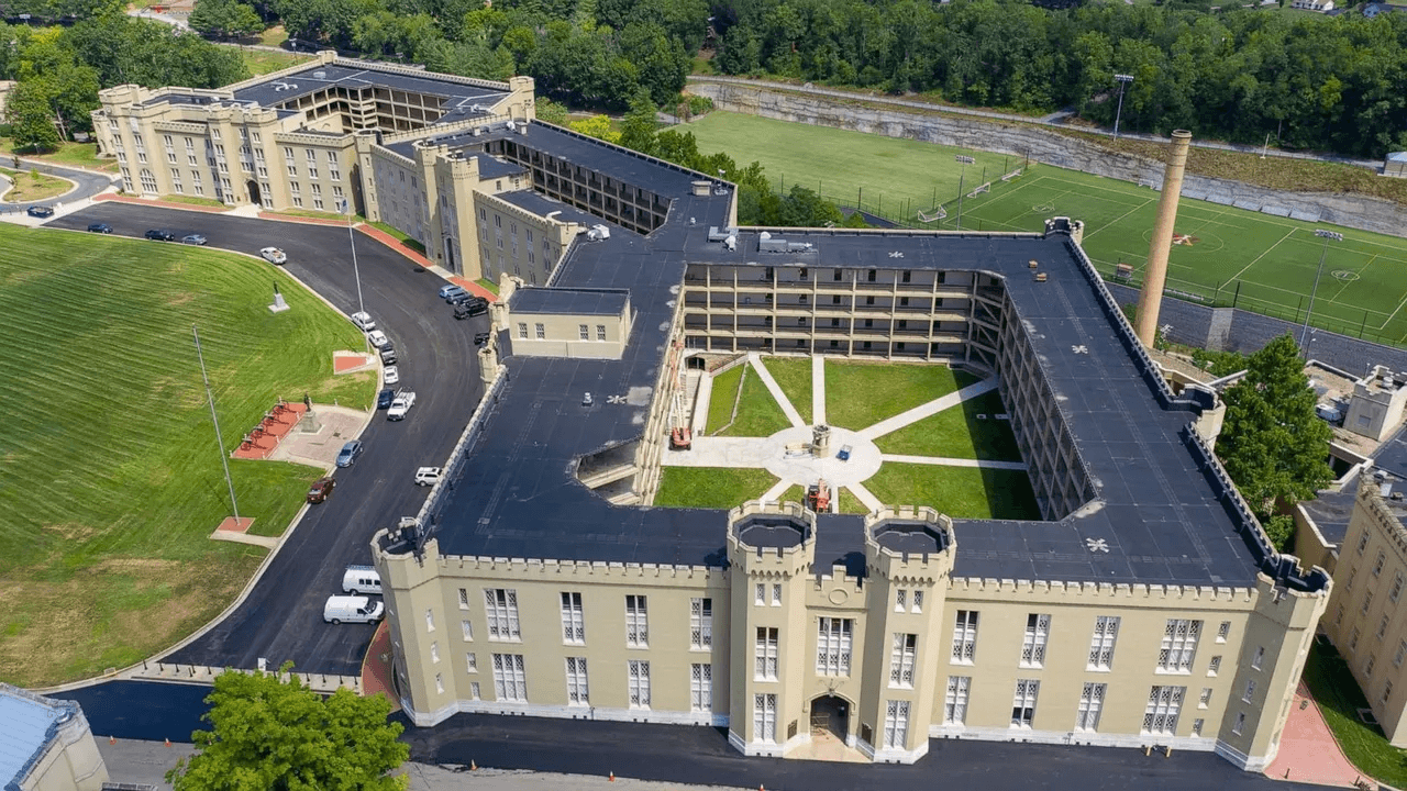 Aerial view of a large, multi-story building with a courtyard and surrounding landscape.