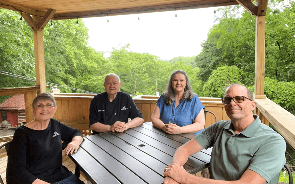 Photo of four family members sitting around an outdoor picnic table.