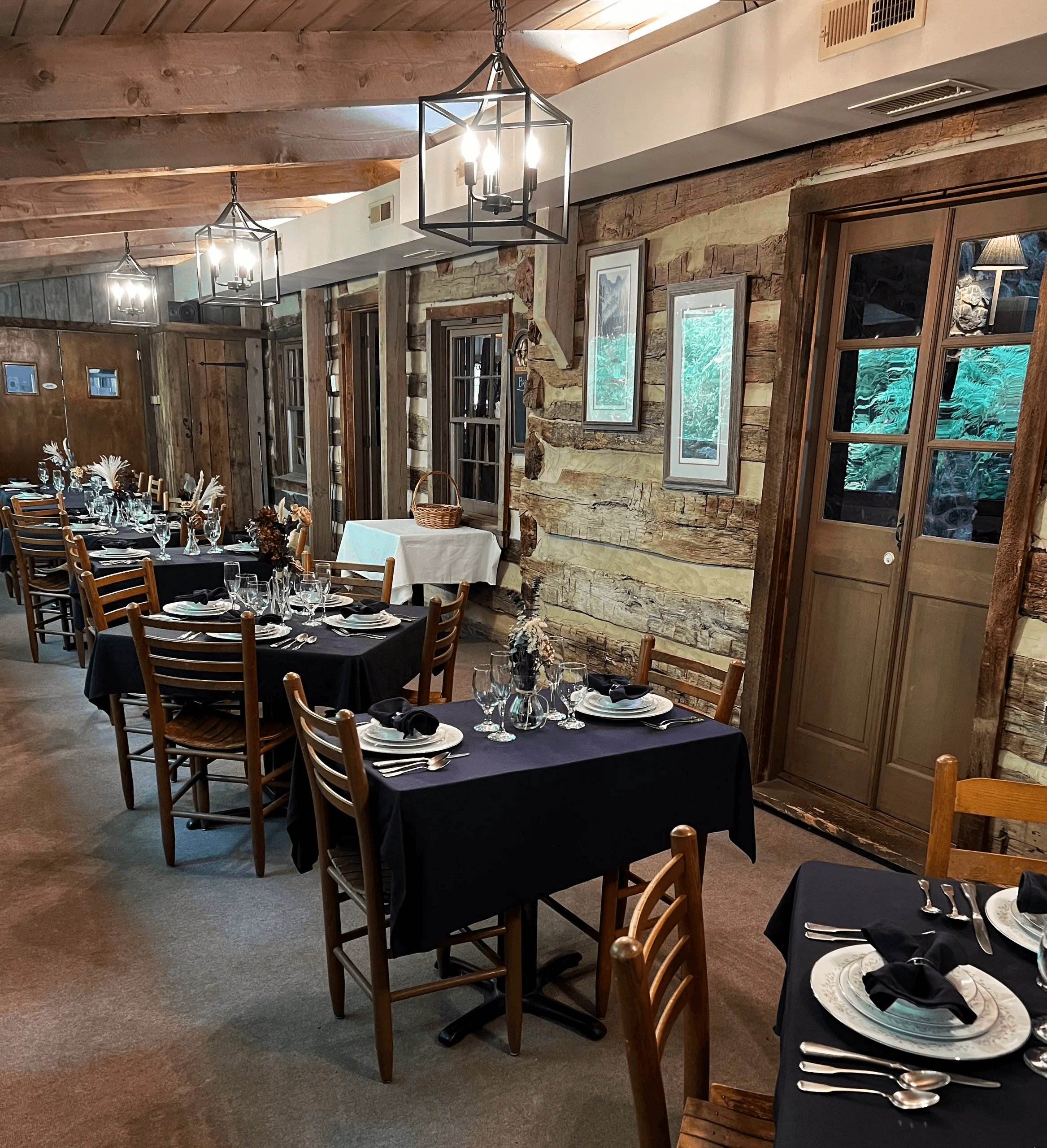 A cozy restaurant interior featuring wooden walls, lantern-style lighting, and elegantly set tables.