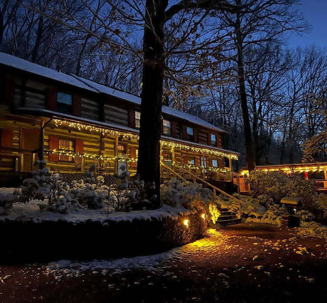 A snow-covered cabin illuminated by warm lights under a twilight sky. A snow-covered cabin illuminated by warm lights under a twilight sky.