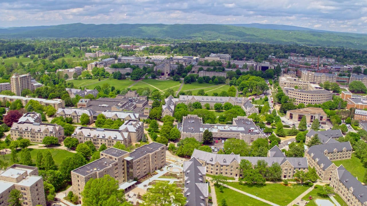 Aerial view of a college campus with green lawns and buildings under a cloudy sky.