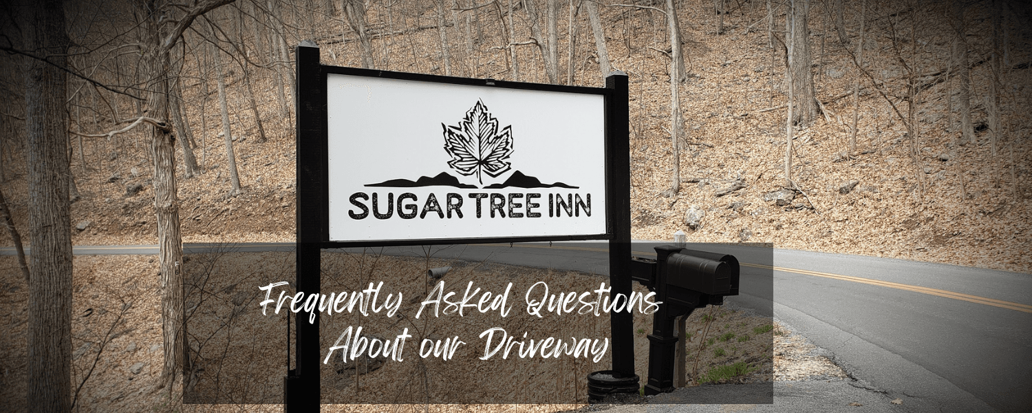Sign for Sugar Tree Inn with a background of bare trees and a winding road. Sign for Sugar Tree Inn with a background of bare trees and a winding road.