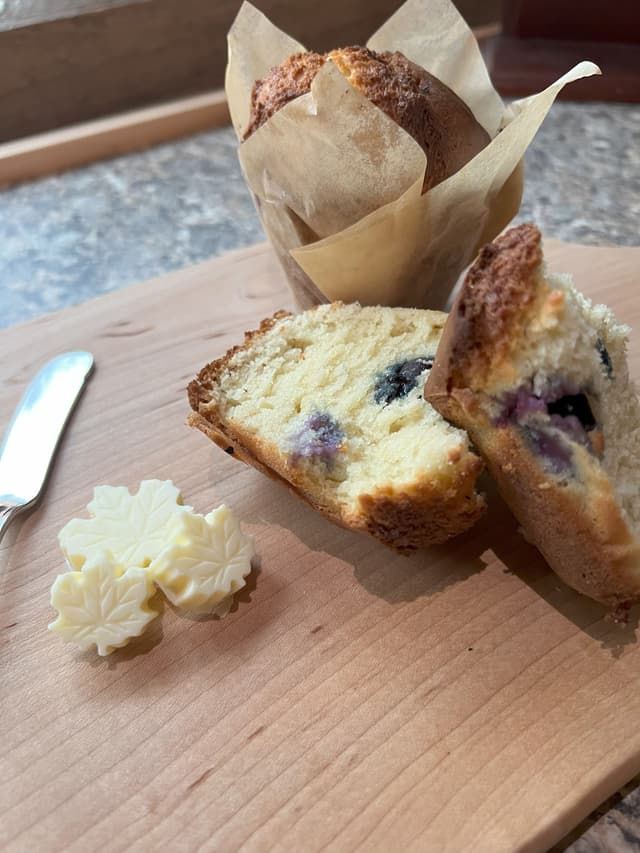blueberry cream muffins on a cutting board with maple leaf shaped butter pats